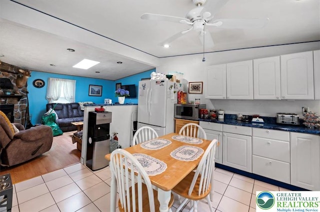 138 Drakes Dr, Penn Forest Twp, PA 18229 - kitchen with freestanding refrigerator, stainless steel microwave, light tile patterned flooring, white cabinetry, and a ceiling fan