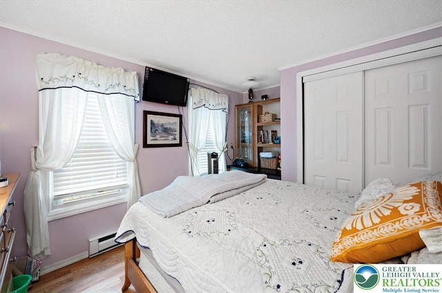 138 Drakes Dr, Penn Forest Twp, PA 18229 - bedroom featuring a closet, wood finished floors, baseboard heating, a textured ceiling, and baseboards