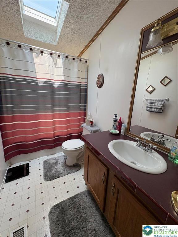 10188 Cork Ln, Upper Macungie Twp, PA 18031 - bathroom featuring a skylight, vanity, toilet, crown molding, and a textured ceiling