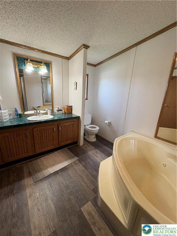10188 Cork Ln, Upper Macungie Twp, PA 18031 - bathroom featuring ornamental molding, wood finished floors, a whirlpool tub, vanity, and a textured ceiling
