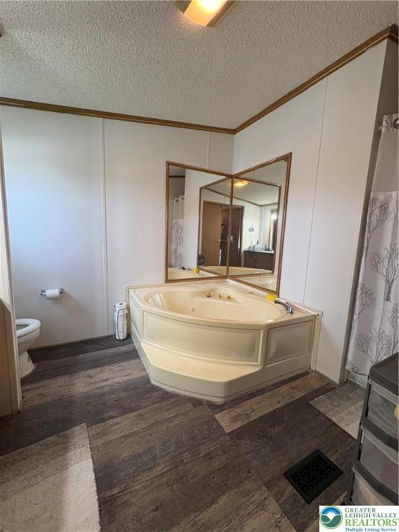 10188 Cork Ln, Upper Macungie Twp, PA 18031 - full bathroom featuring crown molding, wood finished floors, a tub with jets, a textured ceiling, and toilet
