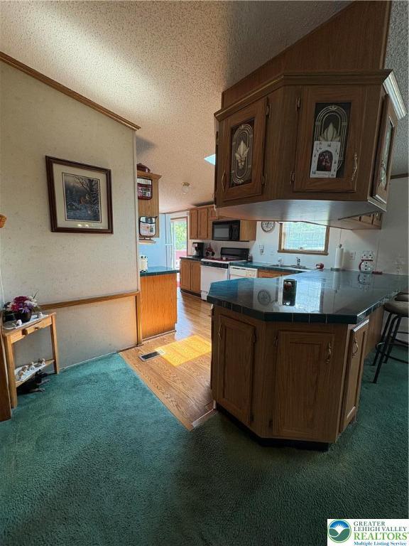 10188 Cork Ln, Upper Macungie Twp, PA 18031 - kitchen featuring light colored carpet, a textured ceiling, a peninsula, white range oven, and black microwave