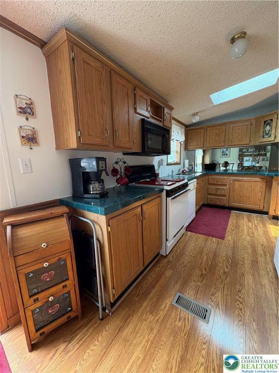 10188 Cork Ln, Upper Macungie Twp, PA 18031 - kitchen with white appliances, a textured ceiling, light wood-type flooring, a skylight, and brown cabinetry