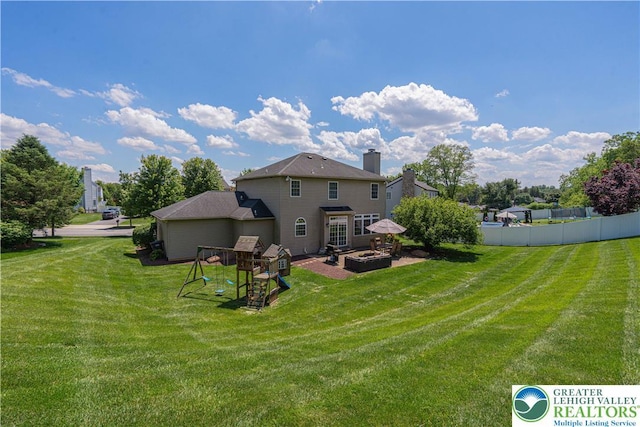 697 Ryan Dr, South Whitehall Twp, PA 18103 - rear view of house with a chimney, a playground, and an attached garage