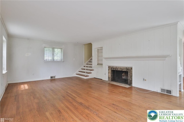 145 N Main St, Allentown City, PA 18104 - unfurnished living room with built in shelves, ornamental molding, wood finished floors, stairs, and a tiled fireplace