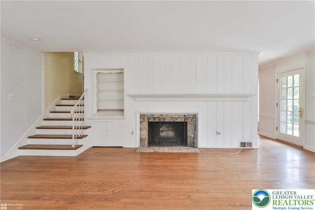 145 N Main St, Allentown City, PA 18104 - unfurnished living room featuring stairway, wood finished floors, a fireplace, built in shelves, and crown molding