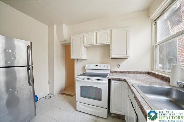 605 N 9th St, Allentown City, PA 18102 - kitchen featuring freestanding refrigerator, white range with electric stovetop, white cabinets, a sink, and light tile patterned floors