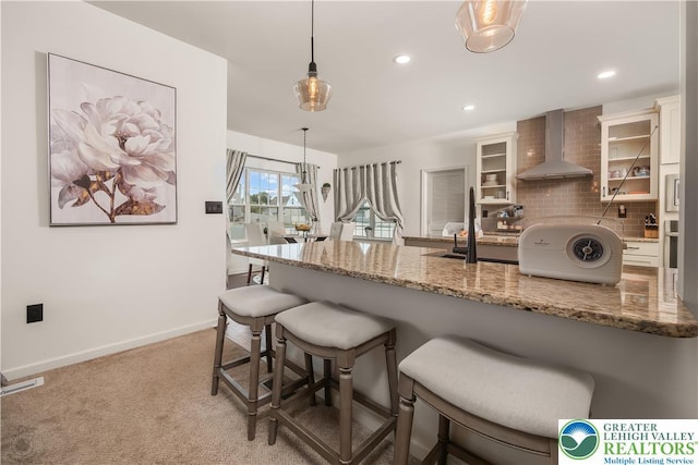 1043 Lisa Ln, Palmer Twp, PA 18045 - kitchen with wall chimney exhaust hood, a kitchen breakfast bar, tasteful backsplash, hanging light fixtures, and glass insert cabinets