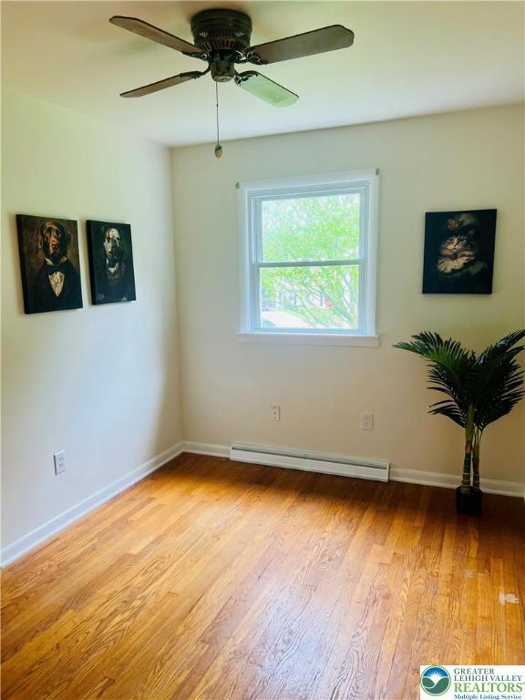 818 W Station Ave, Coopersburg Borough, PA 18036 - empty room featuring a baseboard heating unit, light wood-style flooring, ceiling fan, and baseboards