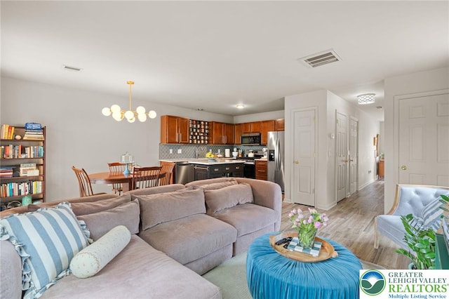 707 Blue Heron Dr, Allentown City, PA 18103 - living room with light wood-style flooring, a chandelier, and baseboards