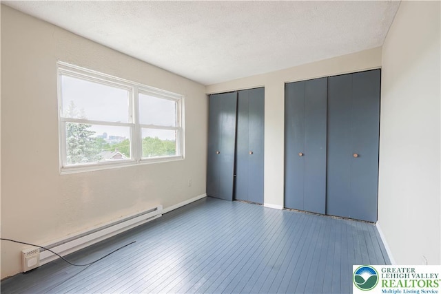 402 Bradford St, Allentown City, PA 18109 - unfurnished bedroom featuring a baseboard radiator, two closets, hardwood / wood-style flooring, baseboards, and a textured ceiling