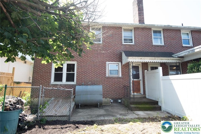 665 Furnace St, Emmaus Borough, PA 18049 - rear view of house featuring heating fuel, brick siding, and a chimney