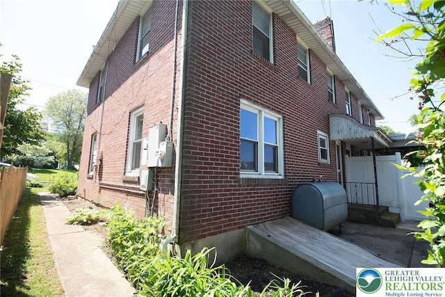 665 Furnace St, Emmaus Borough, PA 18049 - view of property exterior with brick siding, oil tank, and a chimney