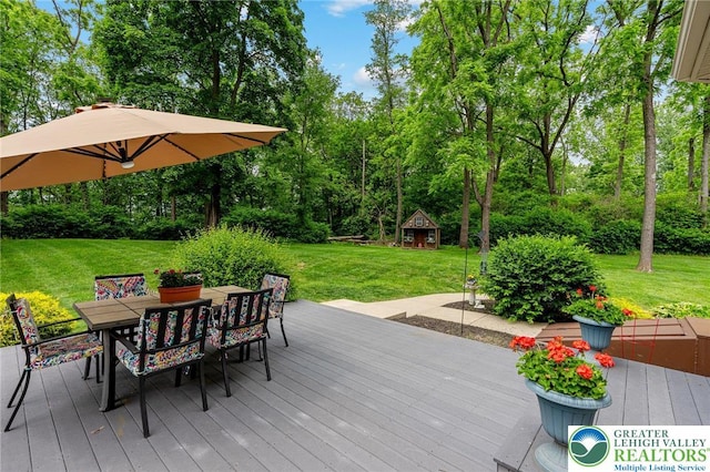 6335 Sweetbriar Ln, Upper Milford Twp, PA 18092 - wooden terrace featuring outdoor dining area, a lawn, view of scattered trees, and an outbuilding