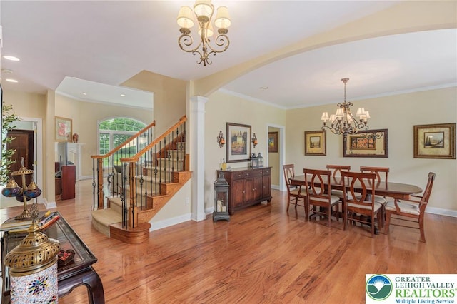 6335 Sweetbriar Ln, Upper Milford Twp, PA 18092 - dining area with arched walkways, light wood-style flooring, a chandelier, ornamental molding, and stairs
