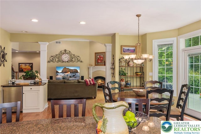 6335 Sweetbriar Ln, Upper Milford Twp, PA 18092 - dining area with ornate columns, light wood-type flooring, a warm lit fireplace, recessed lighting, and arched walkways