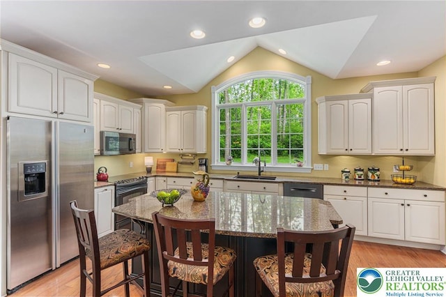 6335 Sweetbriar Ln, Upper Milford Twp, PA 18092 - kitchen featuring stainless steel appliances, light wood-type flooring, a kitchen breakfast bar, dark stone counters, and lofted ceiling