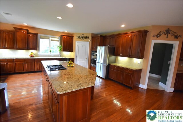 55 Forrest Stand Dr, Easton, PA 18042 - kitchen featuring stainless steel appliances, a center island, wood finished floors, light stone counters, and tasteful backsplash
