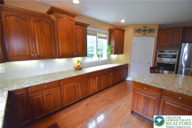 55 Forrest Stand Dr, Easton, PA 18042 - kitchen with appliances with stainless steel finishes, light wood-type flooring, decorative backsplash, light stone countertops, and recessed lighting
