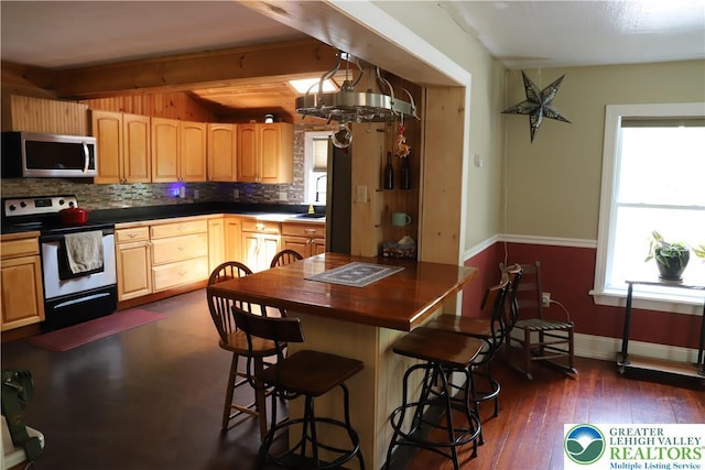118 Burgoon Rd, Stroud Twp, PA 18301 - kitchen featuring appliances with stainless steel finishes, decorative backsplash, dark countertops, a kitchen bar, and beam ceiling
