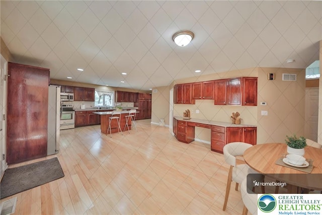 205 Osprey Way, Middle Smithfield Twp, PA 18302 - kitchen with dark brown cabinets, stainless steel appliances, a breakfast bar, light countertops, and a center island