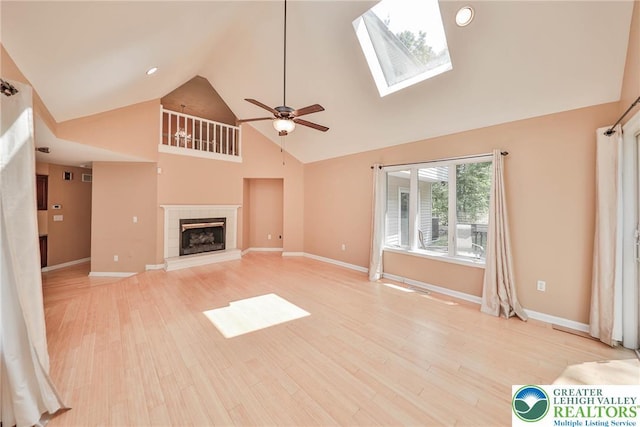205 Osprey Way, Middle Smithfield Twp, PA 18302 - unfurnished living room with high vaulted ceiling, ceiling fan, light wood-style floors, a tile fireplace, and a skylight