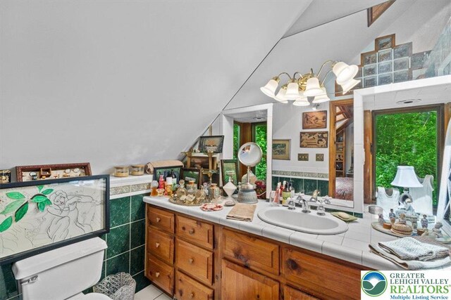 1341 Beaver Valley Rd, Hamilton Twp, PA 18360 - bathroom featuring lofted ceiling, vanity, tile walls, and wainscoting