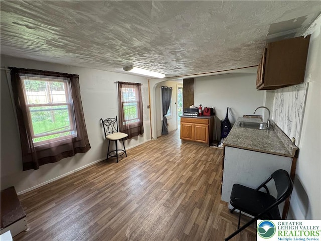 226 E Snyder Ave, Lansford Boro, PA 18232 - kitchen with wood finished floors, arched walkways, dark countertops, a textured ceiling, and brown cabinetry