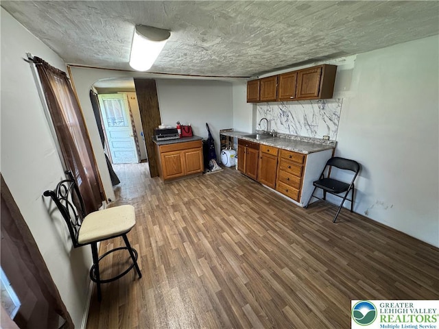 226 E Snyder Ave, Lansford Boro, PA 18232 - kitchen featuring wood finished floors, brown cabinets, arched walkways, and decorative backsplash