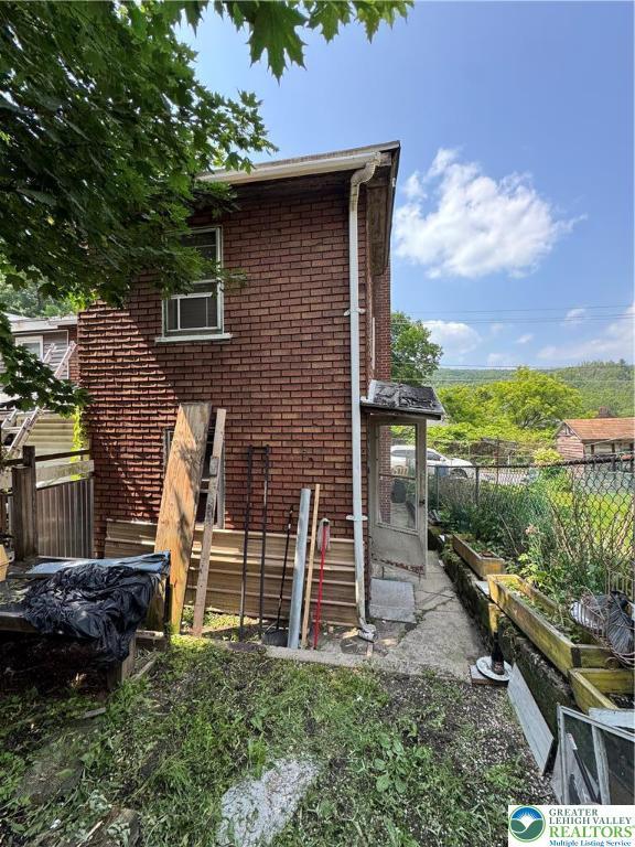 226 E Snyder Ave, Lansford Boro, PA 18232 - rear view of property featuring brick siding and a vegetable garden