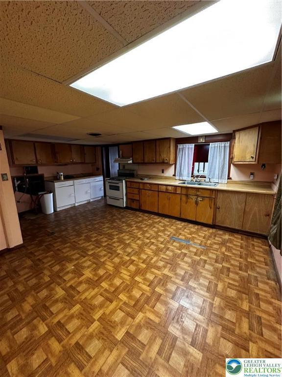 701 N Lacrosse St, Allentown City, PA 18109 - kitchen with white gas range, light countertops, brown cabinetry, and a paneled ceiling