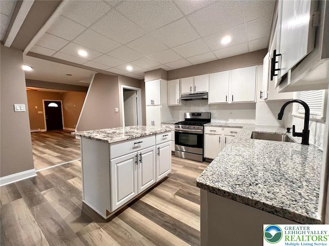 820 Ridge St, West Easton Borough, PA 18042 - kitchen with stainless steel gas range, under cabinet range hood, a kitchen island, white cabinets, and light wood-style floors