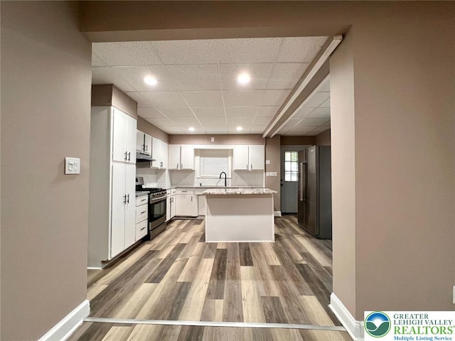820 Ridge St, West Easton Borough, PA 18042 - kitchen featuring stainless steel appliances, under cabinet range hood, a paneled ceiling, wood finished floors, and white cabinetry
