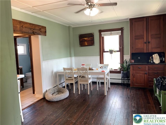 665 Walnut St, Emmaus Borough, PA 18049 - dining space with dark wood-type flooring, a ceiling fan, healthy amount of natural light, wainscoting, and crown molding