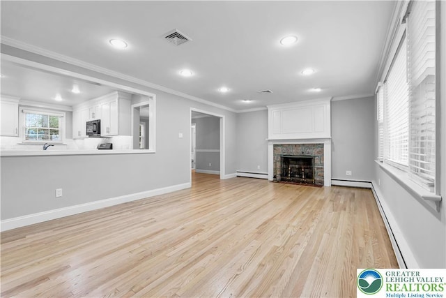 3032 W Woodlawn St, South Whitehall Twp, PA 18104 - unfurnished living room with a baseboard heating unit, recessed lighting, light wood-style flooring, crown molding, and a fireplace with flush hearth