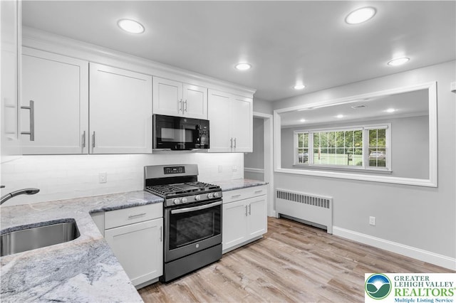 3032 W Woodlawn St, South Whitehall Twp, PA 18104 - kitchen with black microwave, radiator, stainless steel range with gas stovetop, white cabinets, and tasteful backsplash