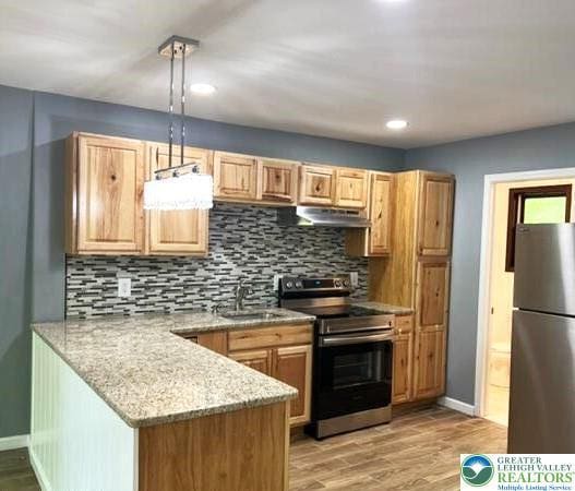 8237 Natures Dr, Coolbaugh Twp, PA 18466 - kitchen with stainless steel appliances, under cabinet range hood, decorative backsplash, a peninsula, and recessed lighting
