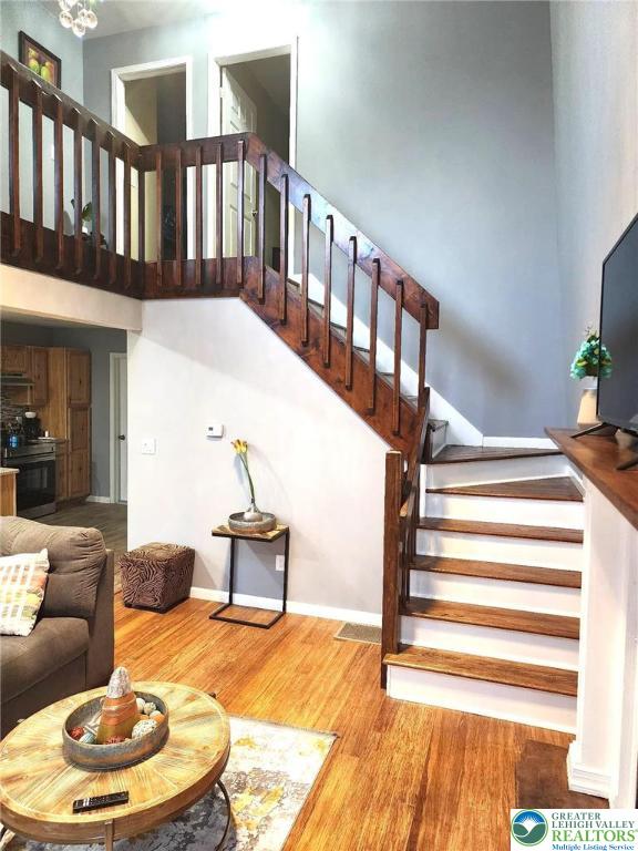 8237 Natures Dr, Coolbaugh Twp, PA 18466 - living room with stairway, wood finished floors, and a towering ceiling