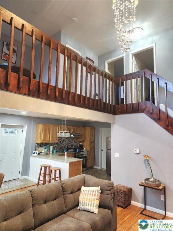8237 Natures Dr, Coolbaugh Twp, PA 18466 - living room featuring light wood-style floors, a high ceiling, and a chandelier