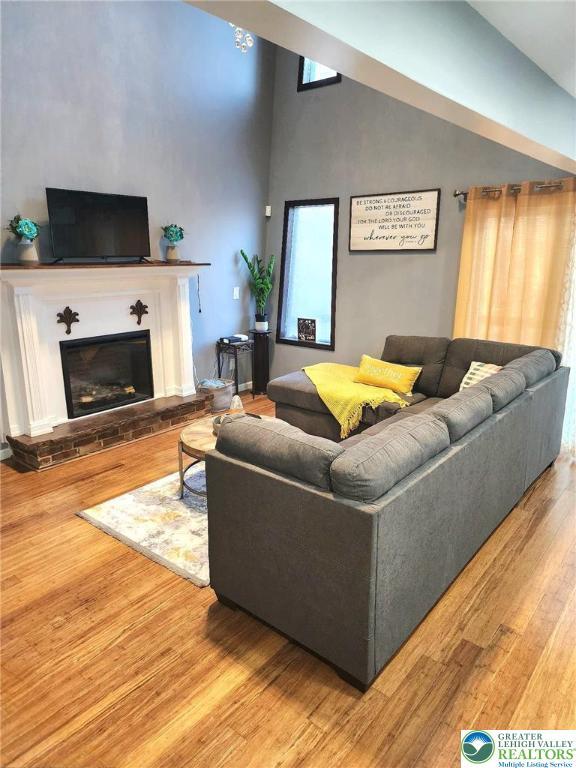 8237 Natures Dr, Coolbaugh Twp, PA 18466 - living room featuring wood finished floors, a glass covered fireplace, and lofted ceiling