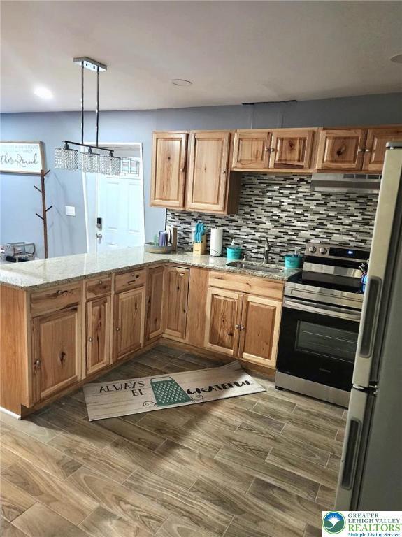 8237 Natures Dr, Coolbaugh Twp, PA 18466 - kitchen featuring stainless steel range with electric stovetop, freestanding refrigerator, extractor fan, a peninsula, and backsplash