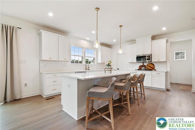 1615 Watson Loop, Upper Macungie Twp, PA 18051 - kitchen featuring stainless steel microwave, tasteful backsplash, a kitchen island, recessed lighting, and white cabinets