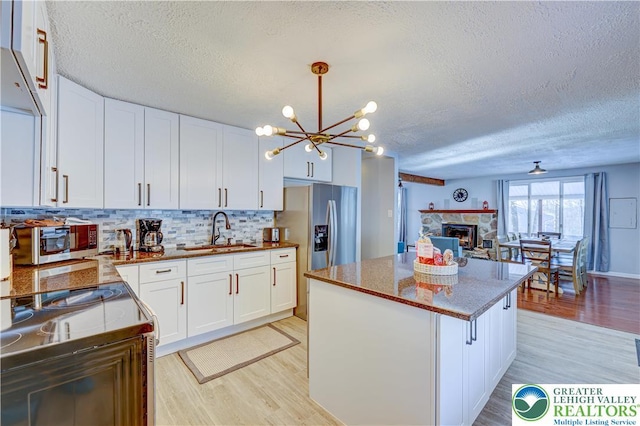 143 Cathleen Dr, Price Twp, PA 18302 - kitchen featuring light wood-style flooring, a textured ceiling, a chandelier, a center island, and electric stove