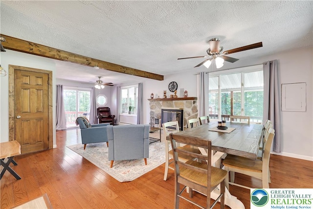 143 Cathleen Dr, Price Twp, PA 18302 - living area featuring a textured ceiling, ceiling fan, light wood-style floors, a stone fireplace, and beamed ceiling