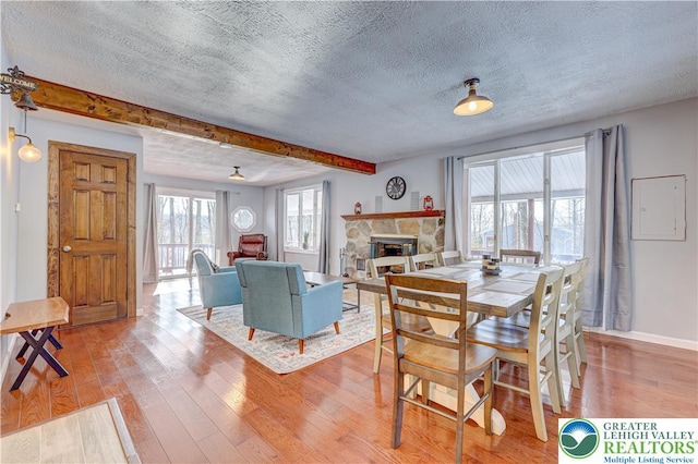 143 Cathleen Dr, Price Twp, PA 18302 - dining area with a textured ceiling, a stone fireplace, light wood-style floors, and beamed ceiling