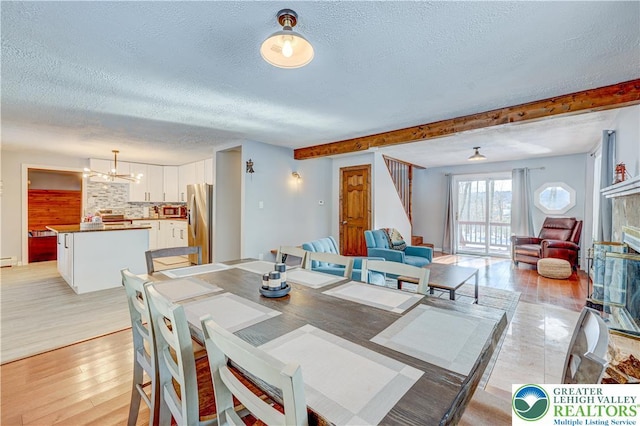 143 Cathleen Dr, Price Twp, PA 18302 - dining space featuring a textured ceiling, light wood-style flooring, a chandelier, stairs, and a baseboard heating unit