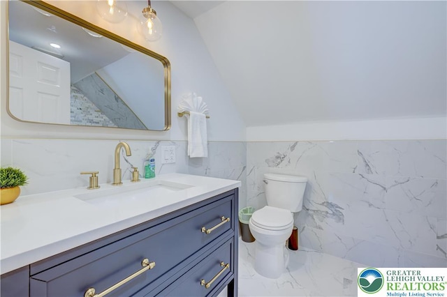 143 Cathleen Dr, Price Twp, PA 18302 - bathroom featuring marble look tile flooring, vanity, tile walls, vaulted ceiling, and a wainscoted wall