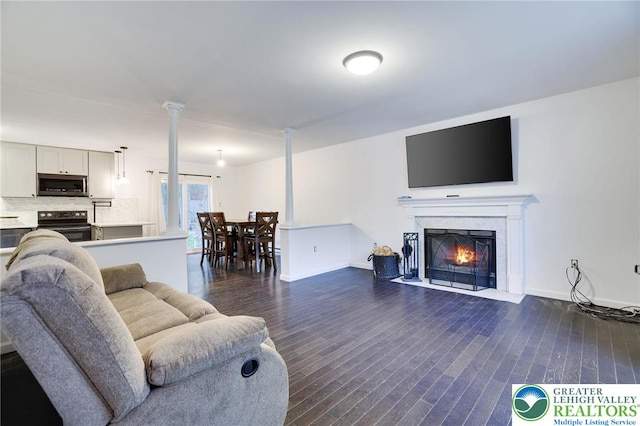 9436 Juniper Dr, Tobyhanna Twp, PA 18466 - living area featuring dark wood-type flooring, a fireplace with flush hearth, and decorative columns