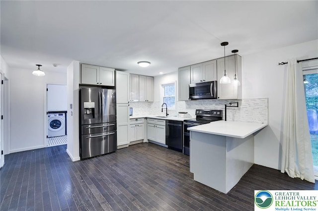 9436 Juniper Dr, Tobyhanna Twp, PA 18466 - kitchen featuring stainless steel appliances, washer / dryer, a peninsula, decorative backsplash, and dark wood finished floors