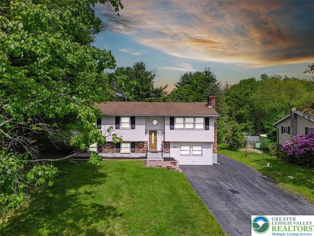 3315 Aspen Rd, Polk Twp, PA 18058 - bi-level home featuring asphalt driveway, a chimney, an attached garage, and a front lawn